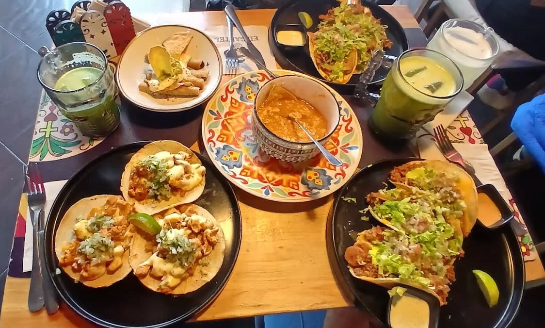 Mesa del local con tacos y bebidas servidos en platos negros y de talavera